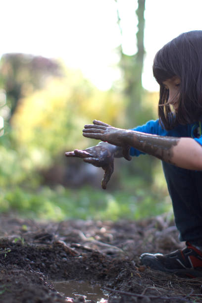 istock Fun grounded child playing in garden, observing mud on hands 1194252613