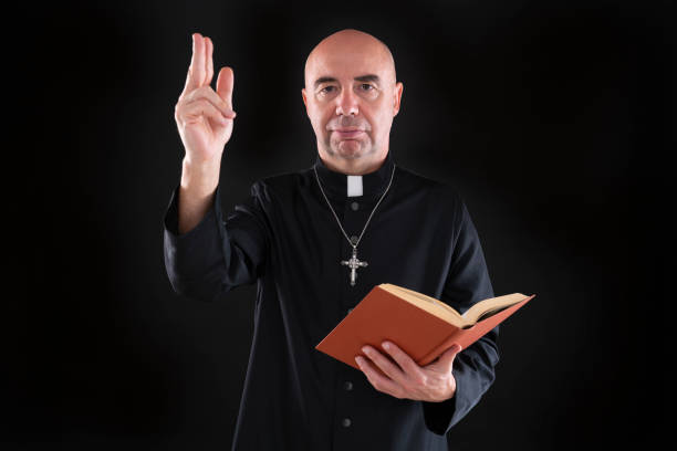 istock Priest with bible blessing hand on low key black 1194252642