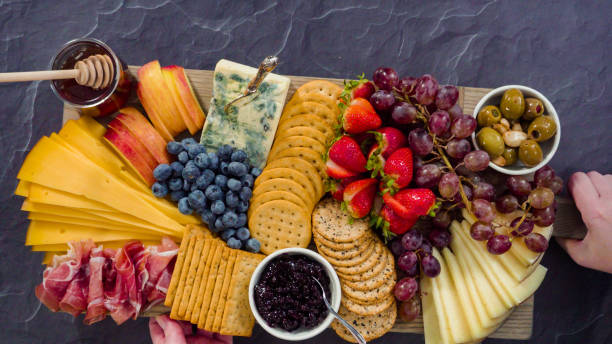 istock Arranging gourmet cheese, crakers, and fruits on a board 1194258384