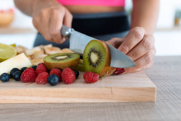 istock Woman's hands cutting kiwi on a wooden table. 1194258732