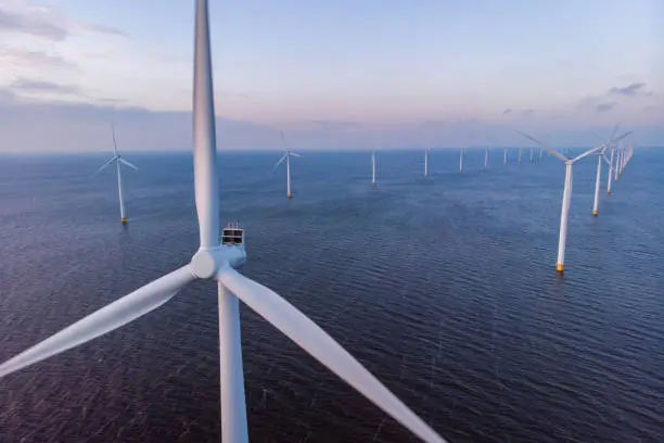 Photo of Windmill park green energy during sunset in the ocean, offshore wind mill turbines Netherlands