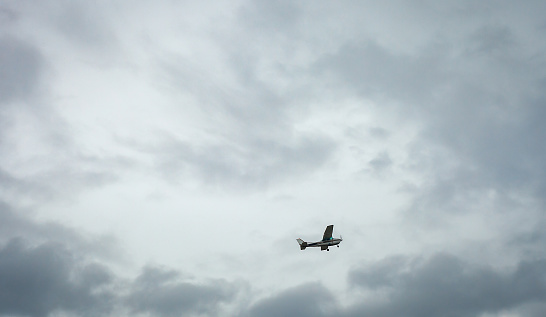 Small private plane flying in cloudy sky. White crop duster flight