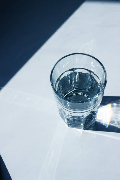 istock Water glass with strong shadows on white background 1194263361