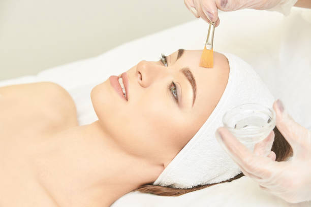 traitement de rétinol de peau de brosse faciale. procédure d'épluchage de femme de beauté. thérapie de jeune fille de cosmétologie. acide hyaluronique - peeling beauty treatment human face beautician photos et images de collection