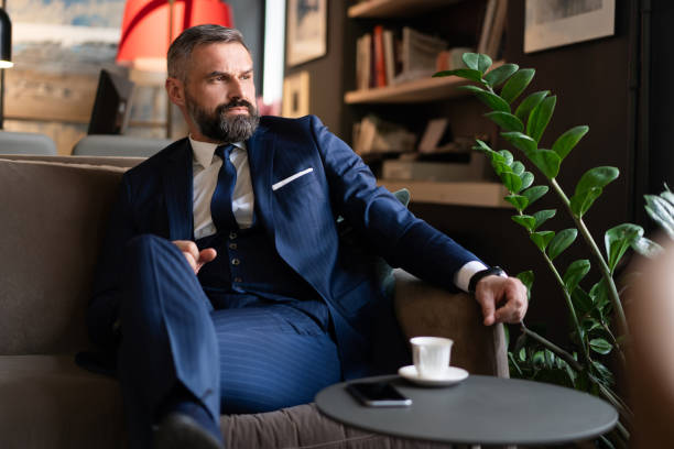 istock Starting new working day. Handsome man holding coffee cup sitting on the couch in office. 1194265593