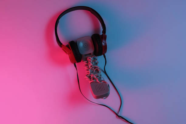istock Old fashioned handset with headphones. Red-blue neon gradient light. Retro wave, pop culture. Top view 1194267086