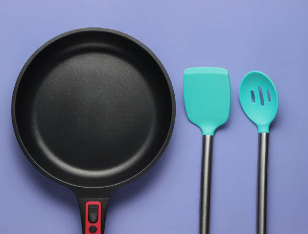 istock Non-stick pan with cooking spatula on purple background. Cooking minimalism concept. Studio shot. Top view 1194268094