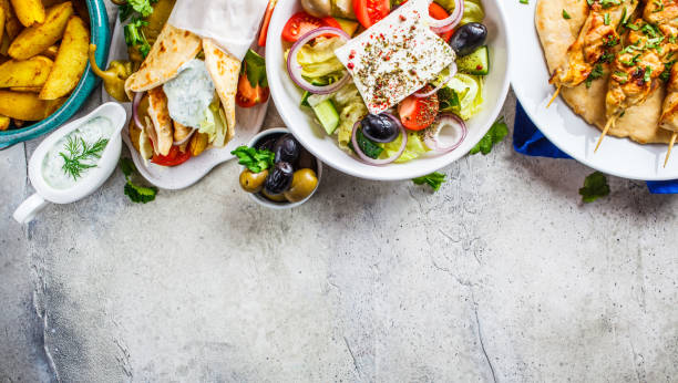 cibo greco: insalata greca, souvlaki di pollo, giroscopi e spicchi di patate al forno su sfondo grigio, vista dall'alto. concetto di cucina tradizionale greca. - greek cuisine greek culture food table foto e immagini stock