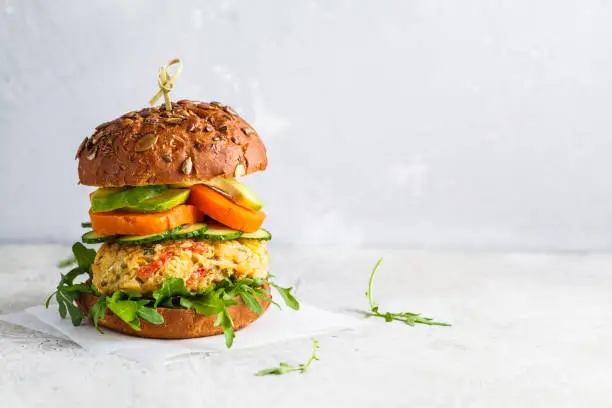 Vegan burger with vegetable cutlet, sweet potato, avocado, cucumber and arugula. Healthy vegan food concept.