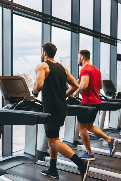 istock Two young man running on treadmill at gym 1194271040