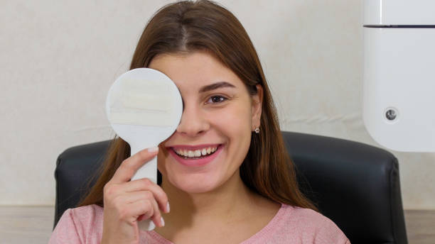 istock Ophthalmology treatment - young smiling woman checking her visual acuity - closing her eye with an eye shield and saying what the projection says 1194271208