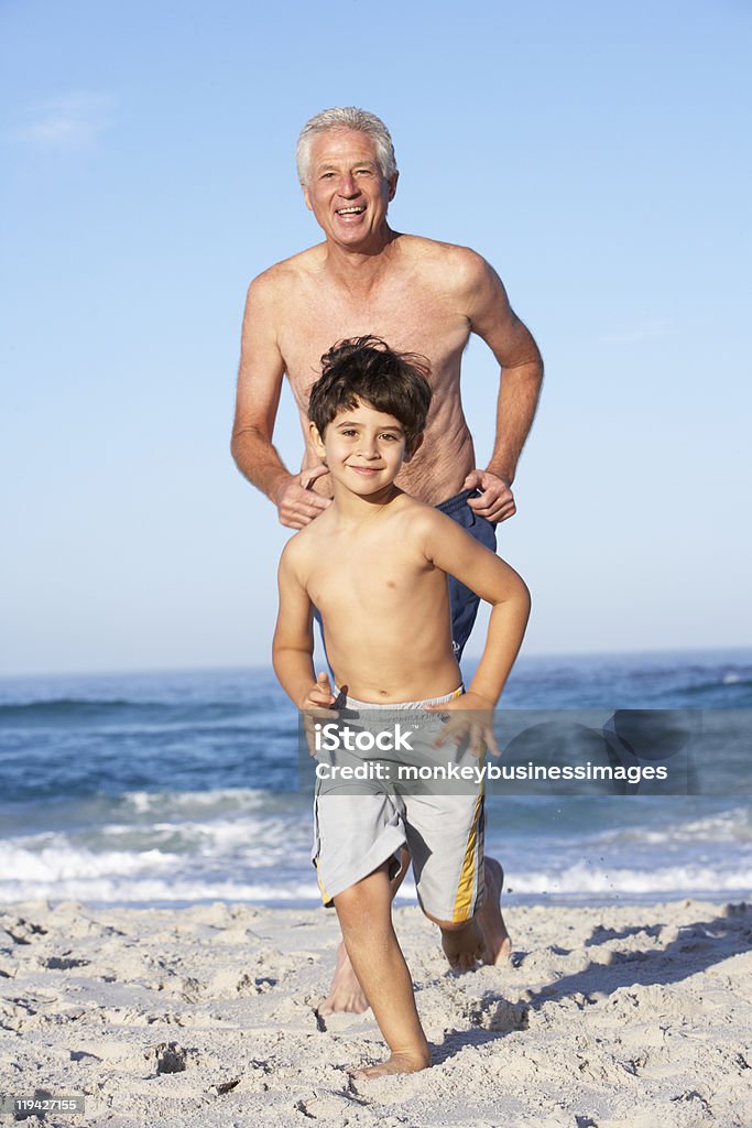 Nonno, padre e nipote che corre lungo la spiaggia - Foto stock royalty-free di Correre