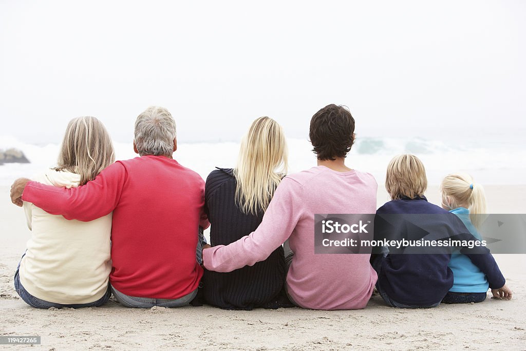 Trois génération famille assis sur la plage de l'hiver - Photo de Vue de dos libre de droits