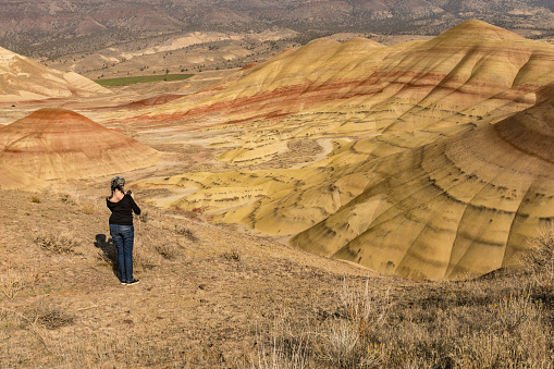 A young brunette with gray hair takes pictures with her smartphone in Painted Hills Overlook, Oregon, USA.