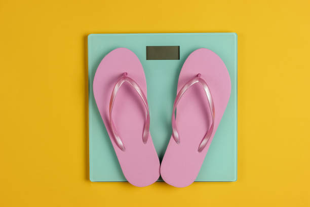 istock Flip flops on the scales. Studio shot on yellow background. Slimming concept. Top view 1194273833