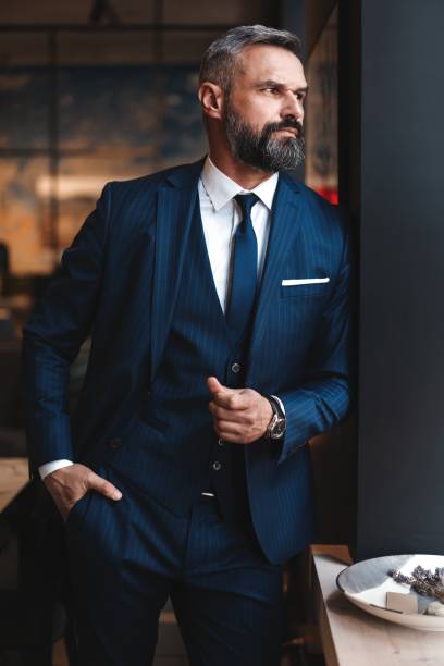 istock Stylish bearded man in a suit standing in modern office 1194274032