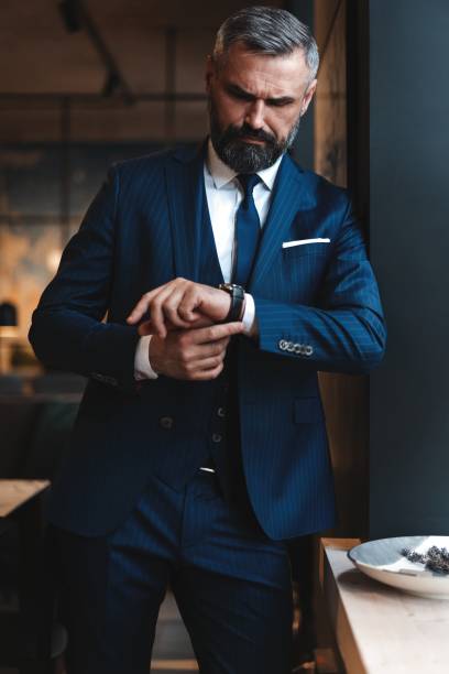 istock Stylish bearded man in a suit standing in modern office 1194274048