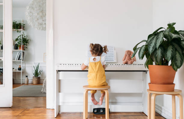 little girl playing piano - piano interior imagens e fotografias de stock