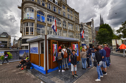 Amsterdam, Holland, August 2019. A kiosk of herring sandwiches and other fresh fish. Some customers are queuing to be served while others are already eating their sandwich