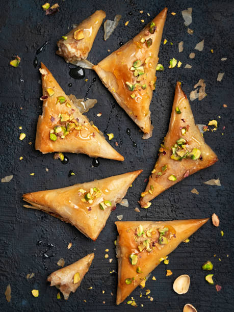 hausgemachtegriechische feta-käse phyllo triangles kuchen mit honig und pistazien. kochen süßigkeiten türkisch, oder arabische traditionelle ramadan gebäck dessert auf einem dunklen hintergrund. ansicht von oben. - filo pastry stock-fotos und bilder