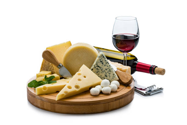 Cheese and wine: cutting board with various cheese slices isolated on white background. A red wine bottle and a wineglass are behind the cheese platter. Useful copy space available for text and/or logo. High resolution 42Mp studio digital capture taken with Sony A7rii and Sony FE 90mm f2.8 macro G OSS lens