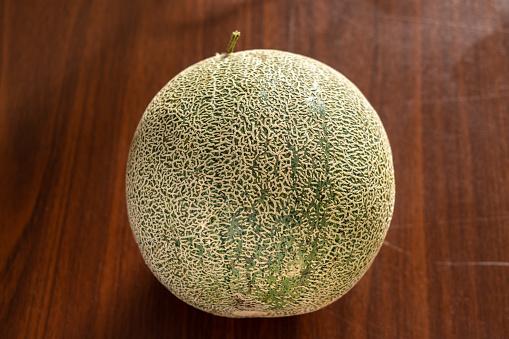 A green melon isolated on wooden background