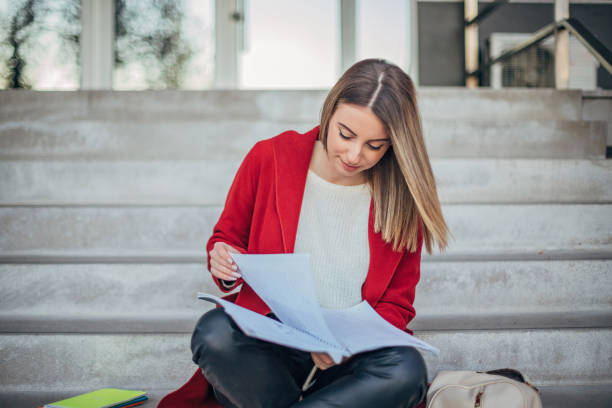 istock Female student sitting on the steps in front of university building 1194284399