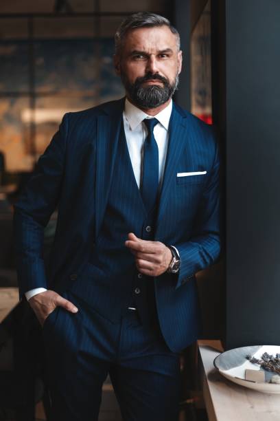 istock Stylish bearded man in a suit standing in modern office 1194284568