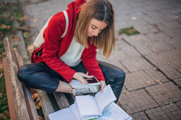 istock Female student reading book and learning fo exam on the bench 1194284623