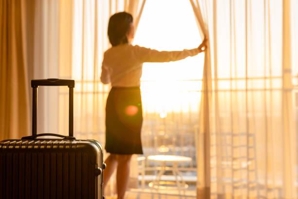 Asian businesswoman pulling the curtains to see the view stock photo