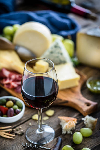 istock Appetizer: red wineglass, cheese and cured ham on rustic wooden table 1194287498