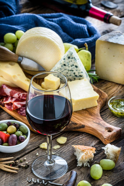 istock Appetizer: red wineglass, cheese and cured ham on rustic wooden table 1194287621