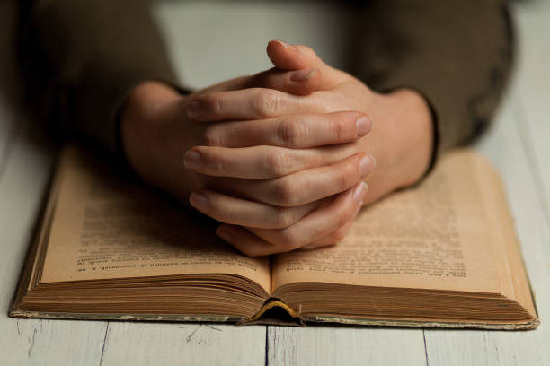 istock Female praying hands on an open bible 1194288521