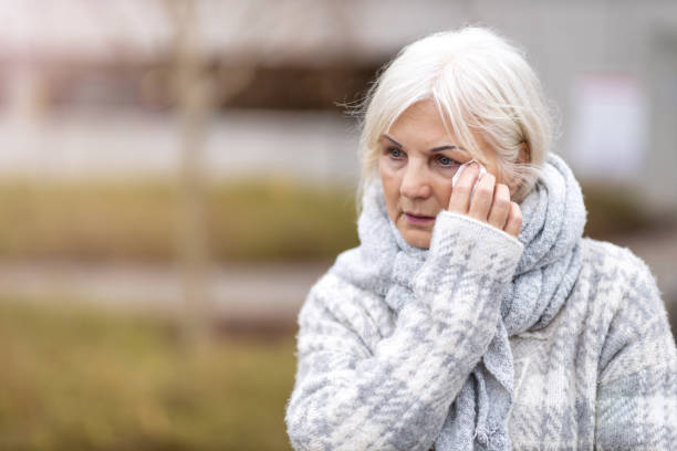 istock Weeping old woman wipes her eyes with tissue 1194294204
