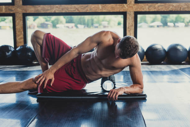 athlète utilisant un rouleau de mousse - glutes relaxation exercise muscular build human muscle photos et images de collection