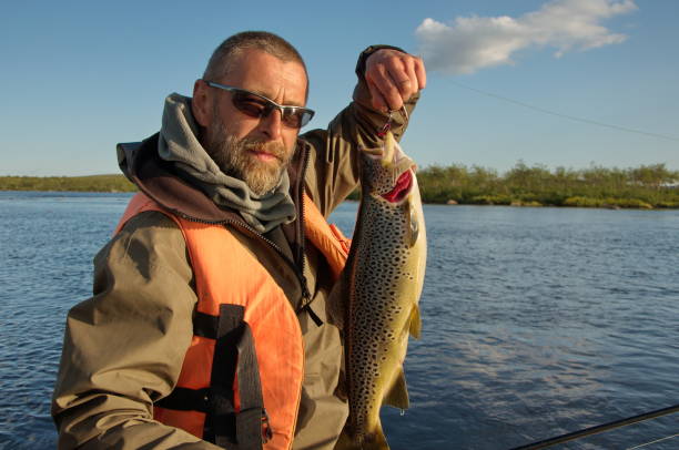 istock Fisherman in sunglasses hold a big brown trout. 1194301817