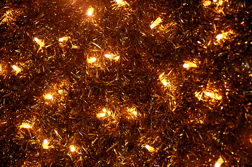 Part of Christmas decorative yellow and white flashing lights, close up. Detail of New Year and Christmas decorations, string rice lights bulbs. Ornaments to christmas celebration, holiday scene.