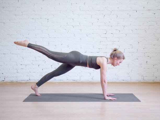 istock Caucasian woman doing plank on mat in pilates studio, one leg up, side view. 1194302117