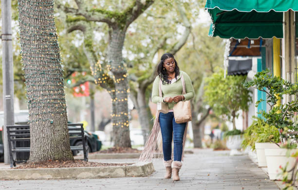 donna afroamericana che cammina sul marciapiede della città - 30s women sweater female foto e immagini stock