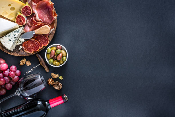 istock Appetizer frame: red wine, cured ham and cheese on on black background 1194304789