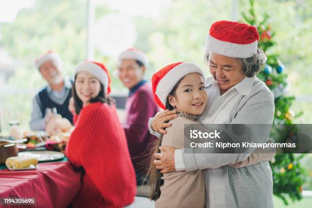 Big Asian Family Celebration In Christmas Day Grandmother Hug And Looking At Granddaughter In Front Of Meal Table Of Family Which Smiling And Felling Happy At Home Merry Xmas And Happy New Year - Fotografias de stock e mais imagens de Família