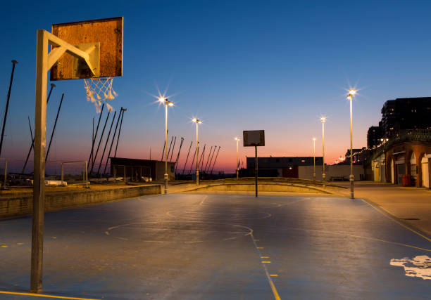 Outdoor empty basketball court on Brighton seafront at dusk.