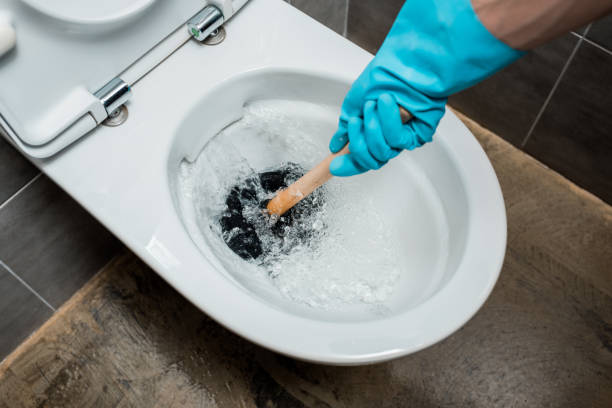 vista recortada del fontanero usando émbolo en el inodoro durante el lavado en el baño moderno con azulejogris - plunger fotografías e imágenes de stock