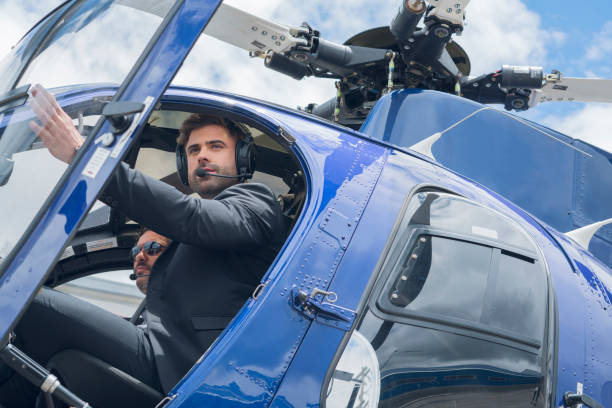 istock Latin executive coopilot man in a beautiful blue helicopter opens one of its doors to get rid of the helicopter dressed in formal suit and next to it the official helicopter pilot 1194308167