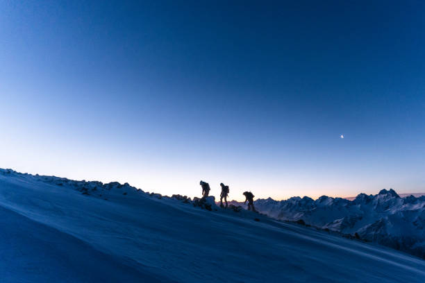 istock Mountaineers ascend snowy ridge at sunrise 1194308233