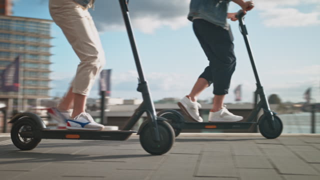 Couple driving electric kick scooters in city