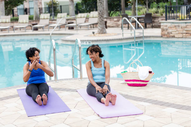 istock Identical twins sitting on yoga mats by pool 1194310267