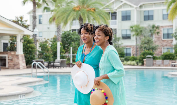 istock Identical twins standing by pool, holding sun hats 1194311065