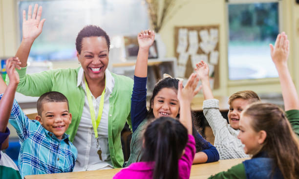 教師、小学生が授業で手を挙げる - elementary school waist up indoors childhood ストックフォトと画像