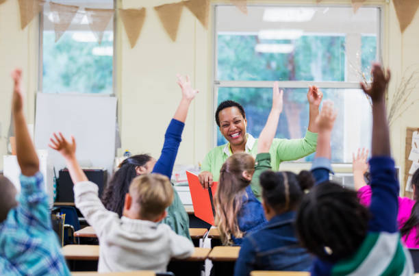 insegnante afro-americano che legge ai bambini delle scuole - woman with arms raised back view foto e immagini stock